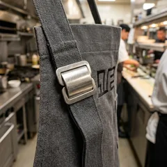 Stainless steel neck strap slider on a kitchen apron