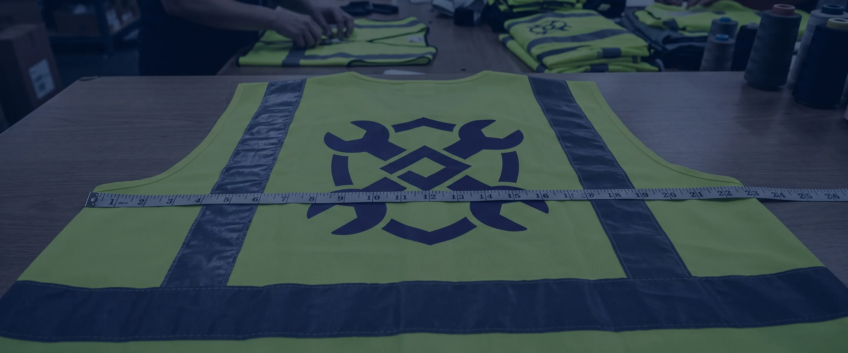 Measuring tape lying across the back logo of a flat safety vest