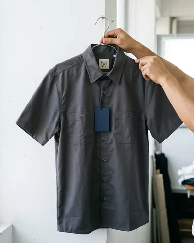 An approved sample work shirt on a hanger with a plain navy swing tag